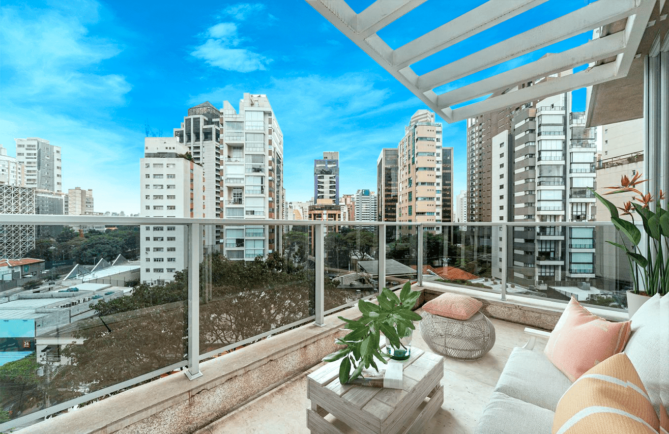 Imagem de um deck de apartamento, da perspectiva de quem está dentro do imóvel, olhando para fora. A vista é de diversos apartamentos em São Paulo.