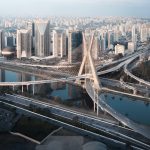 Vista aérea da arquitetura de São Paulo com prédios modernos, vias expressas e rio que atravessa a cidade.