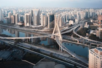 Vista aérea da arquitetura de São Paulo com prédios modernos, vias expressas e rio que atravessa a cidade.